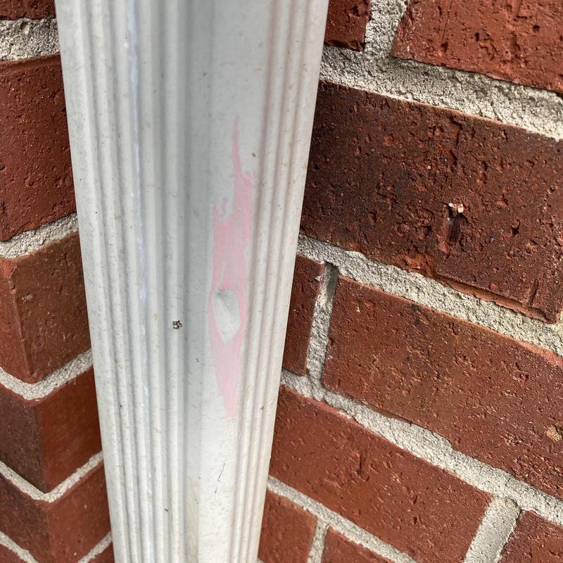 Gutter downspout damage with paint peeling on brick wall Gutter downspout damage with paint peeling on brick wall