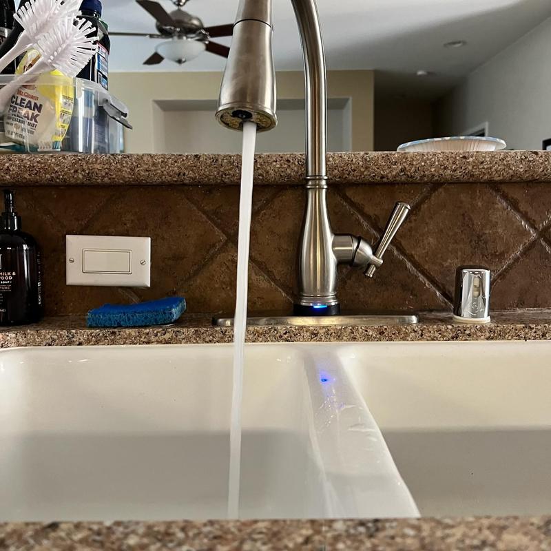 Kitchen faucet with running water over sink basin