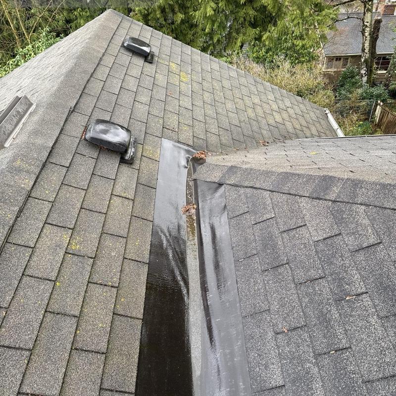 Roof valley flashing and shingle inspection on residential roof