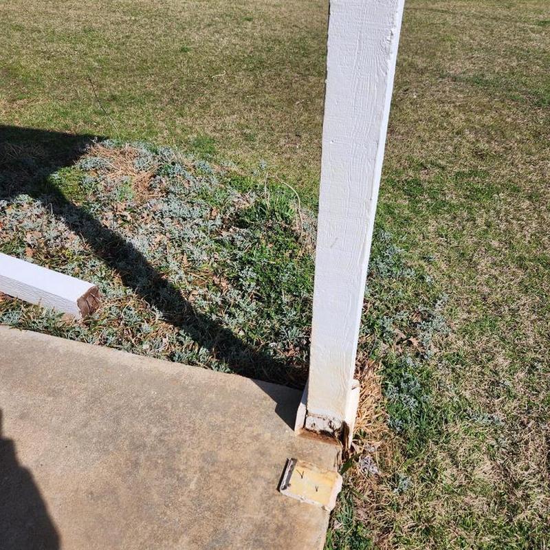 Patio support post with rotted base near concrete slab