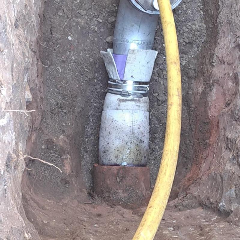 Clay sewer pipe section with metal couplings in trench