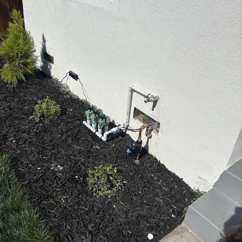 Irrigation valve assembly with solenoid controls near house wall