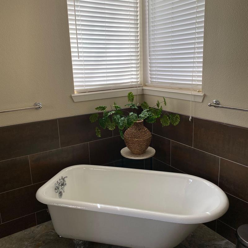 Clawfoot tub with dark tile surround in bathroom corner Clawfoot tub with dark tile surround in bathroom corner