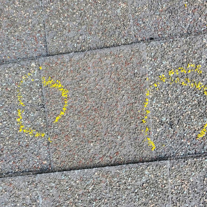Asphalt roof shingles hail damage marked with yellow circles