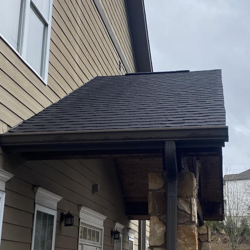 Asphalt shingle roof section with gutter on house exterior