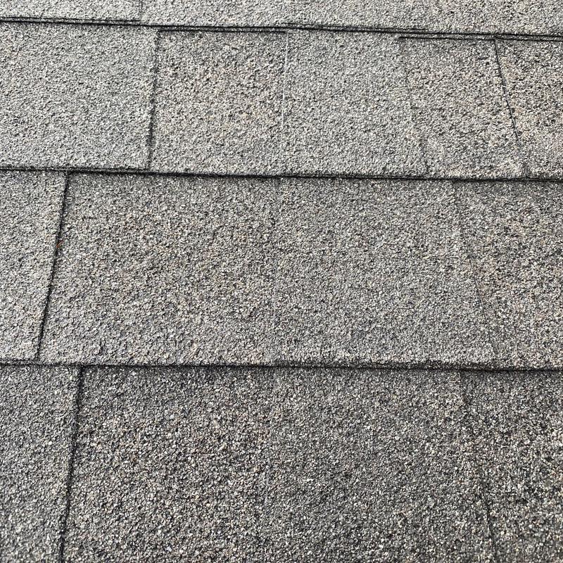 Asphalt shingle roofing close-up showing repair patch