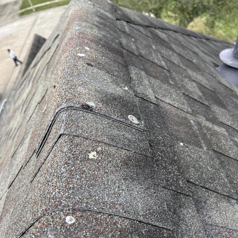 Asphalt shingle ridge cap with hail impact damage