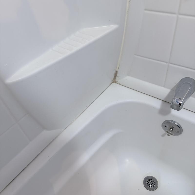 Shower tub corner with old caulk and faucet