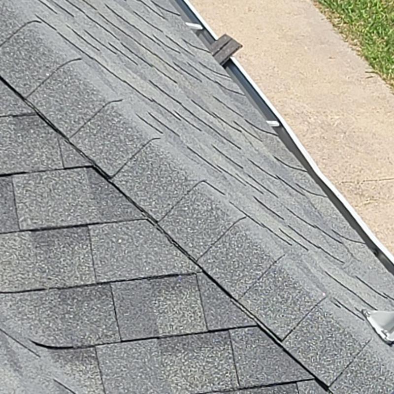 Asphalt roof shingles with hail damage near gutter