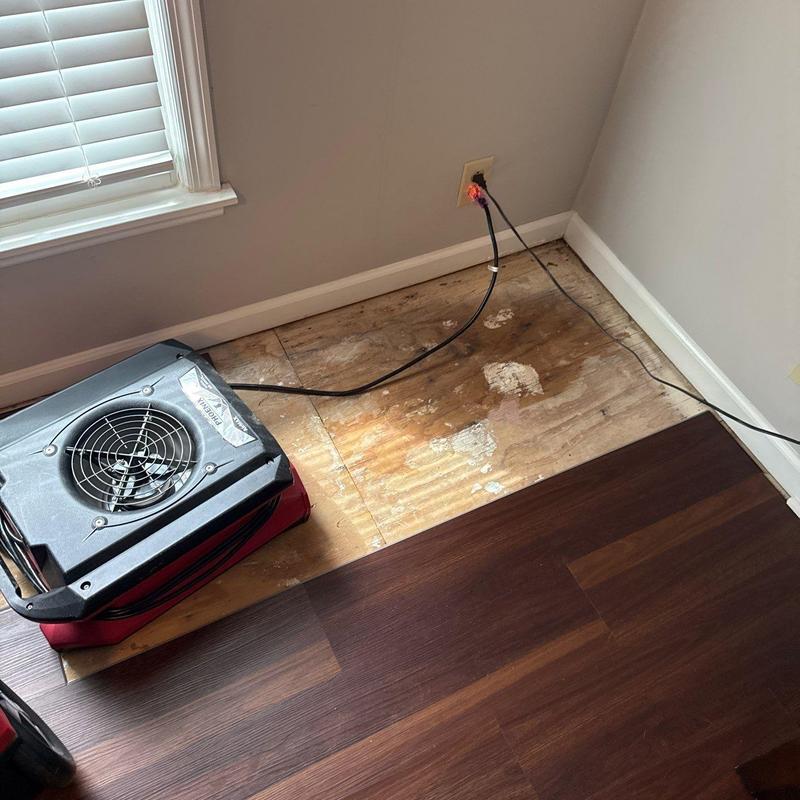 Hardwood floor water damage drying fan in corner