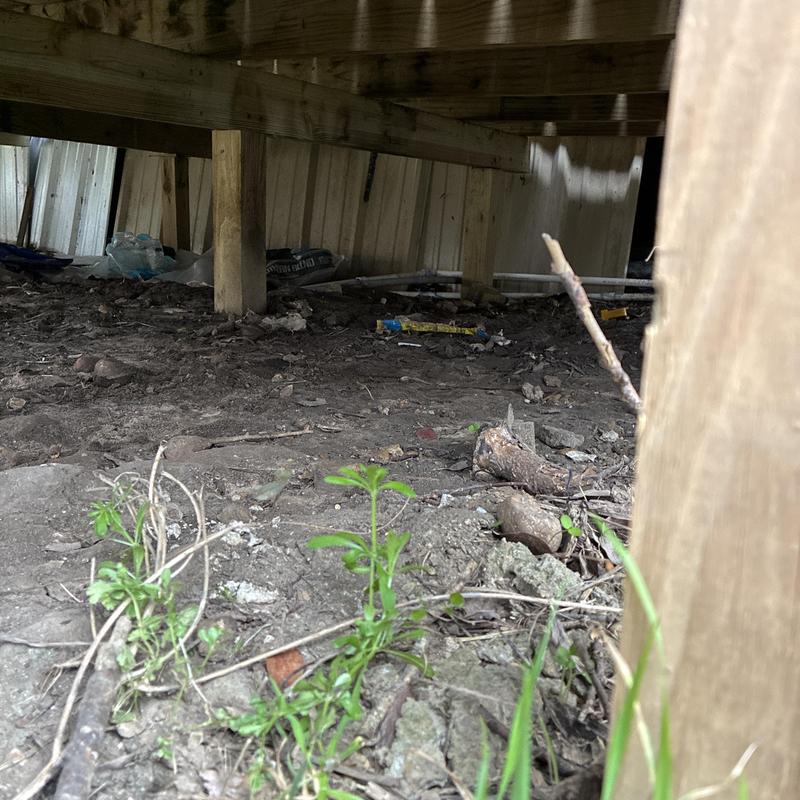 Outdoor water line piping under deck near shed