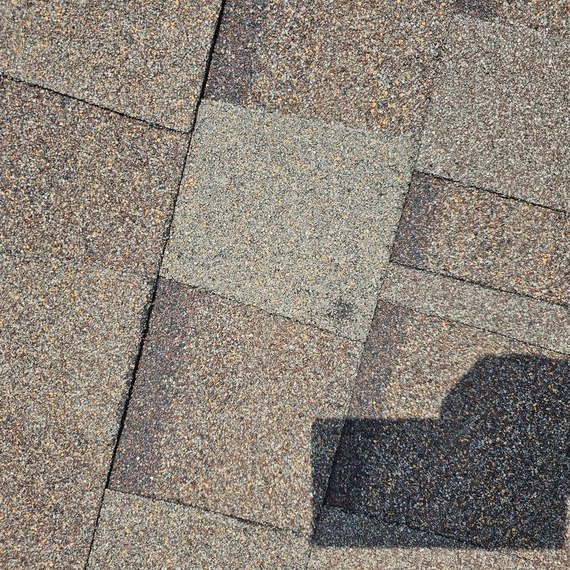 Asphalt roofing shingles with hail damage and repair patch