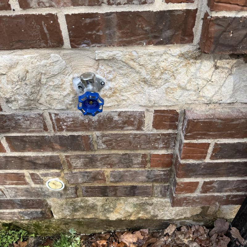 Hose bib valve on exterior brick wall