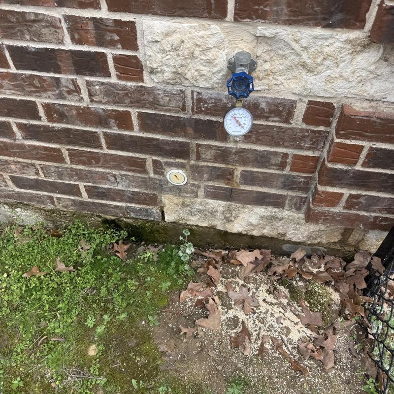 Hose bib valve with pressure gauge on brick wall
