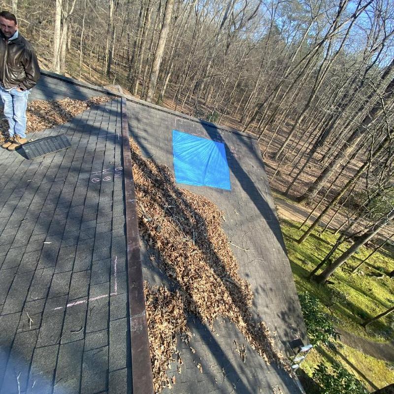 Asphalt shingle roof with blue tarp over damage