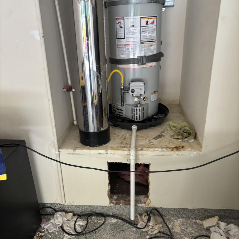 Water heater with damaged drain pipe and hole in wall
