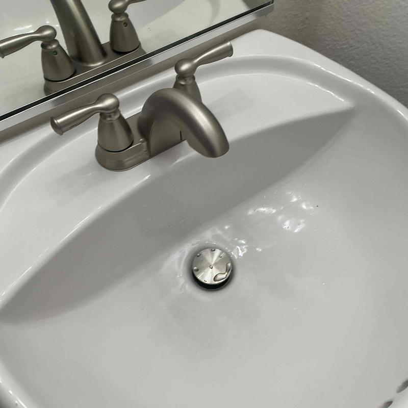 Vanity faucet and pop-up drain assembly in bathroom sink