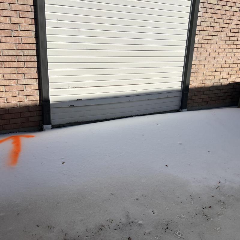 Slab water line leak marked on snow near garage door