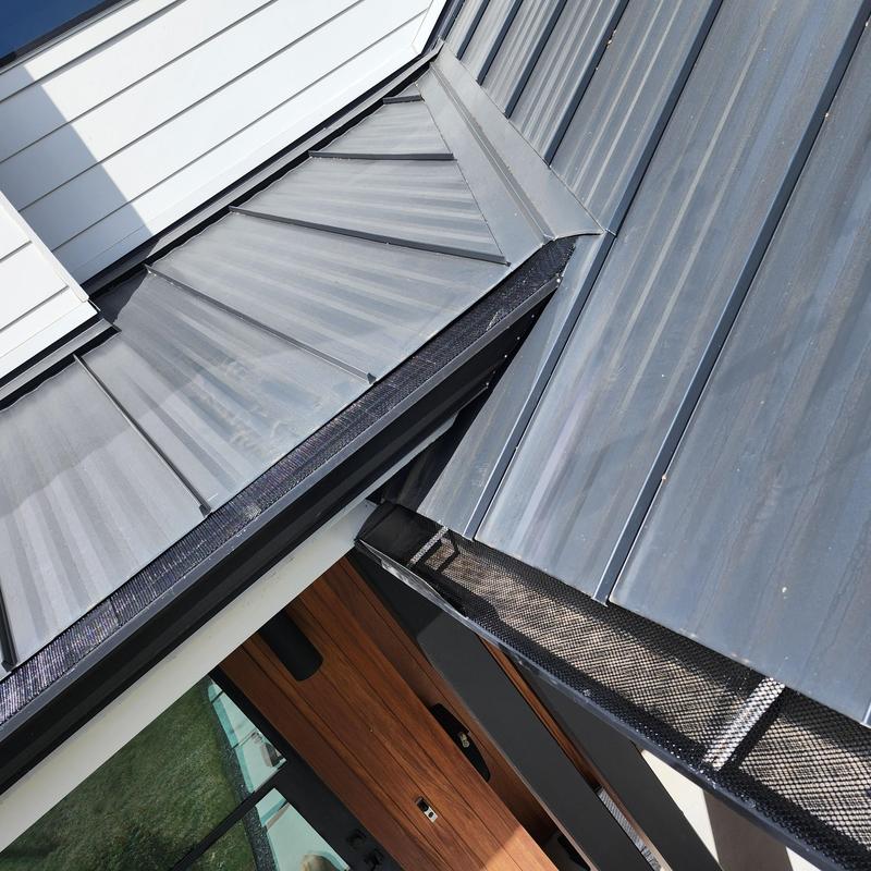 Metal roof panels with installed gutter guards