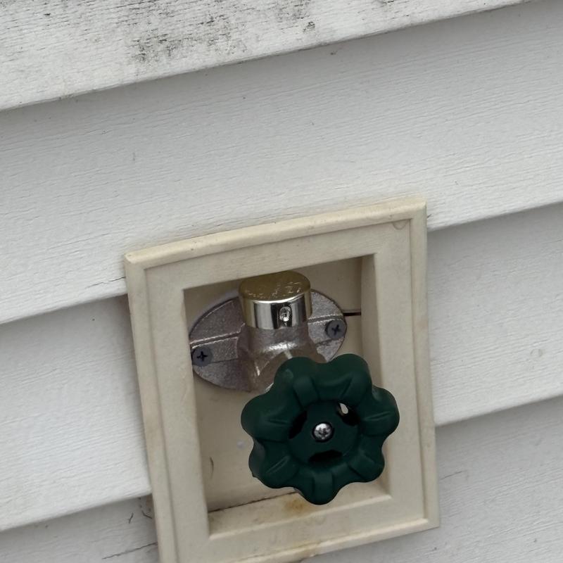 Frost-free outdoor faucet with green handle in wall recess