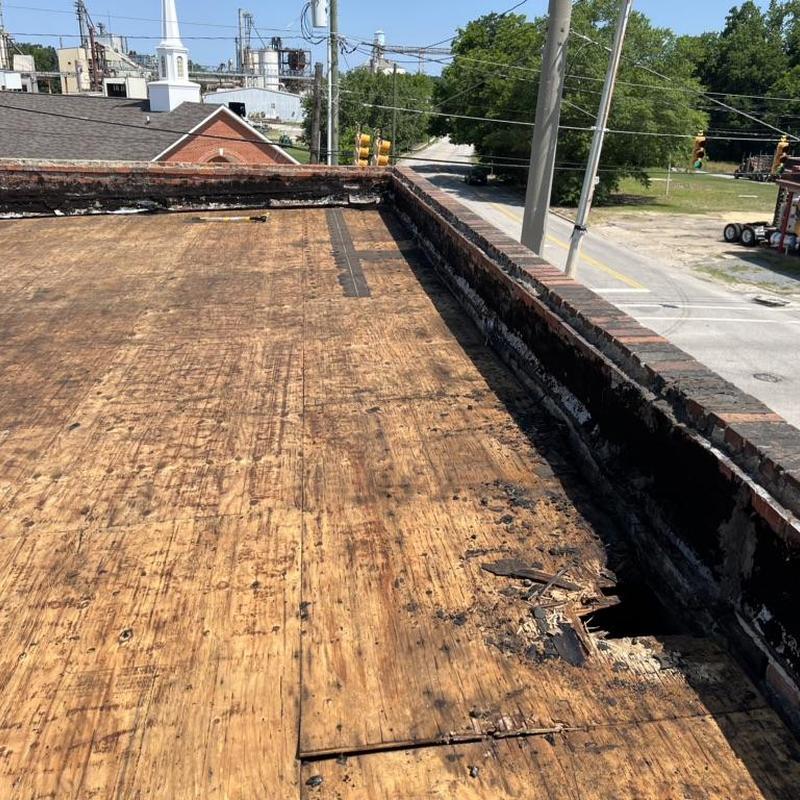 Rolled roofing with damaged plywood deck on commercial roof