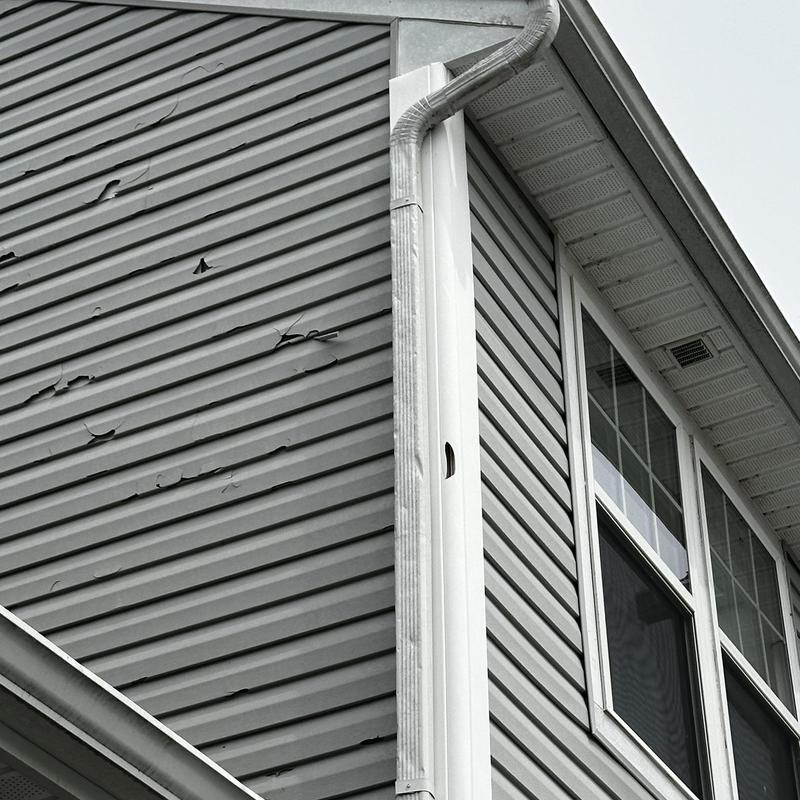 Vinyl siding storm damage with dented gutter and window Vinyl siding storm damage with dented gutter and window