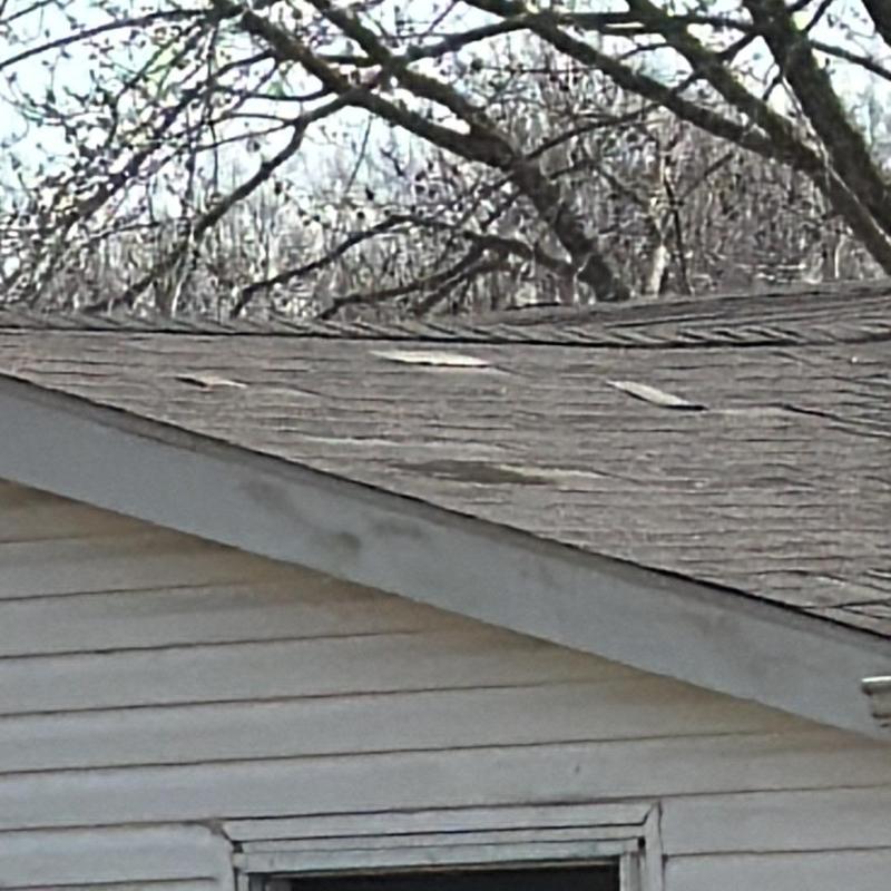 Roof shingles with wind damage on house roof