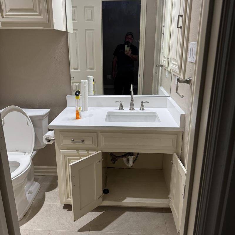 Bathroom sink drain pipes under vanity with open cabinet