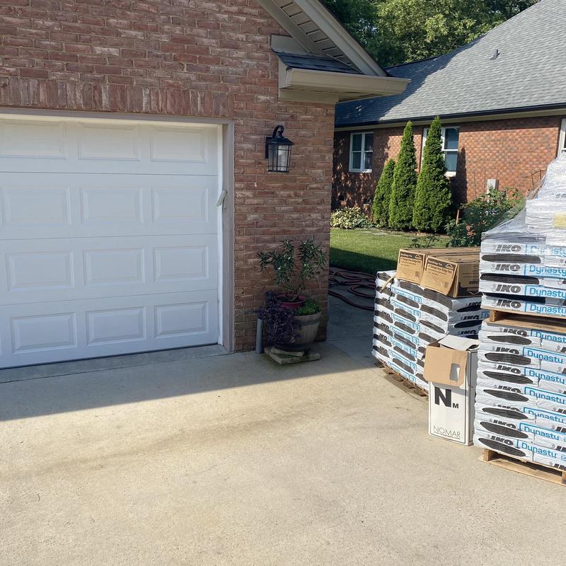 IKO Dynasty roofing shingles stacked outside brick garage IKO Dynasty roofing shingles stacked outside brick garage