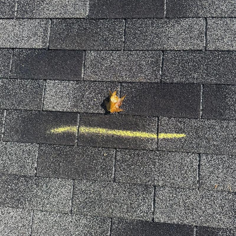 Asphalt shingles with yellow chalk mark and leaf