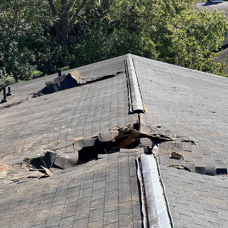 Asphalt shingle roof with large storm damage holes Asphalt shingle roof with large storm damage holes