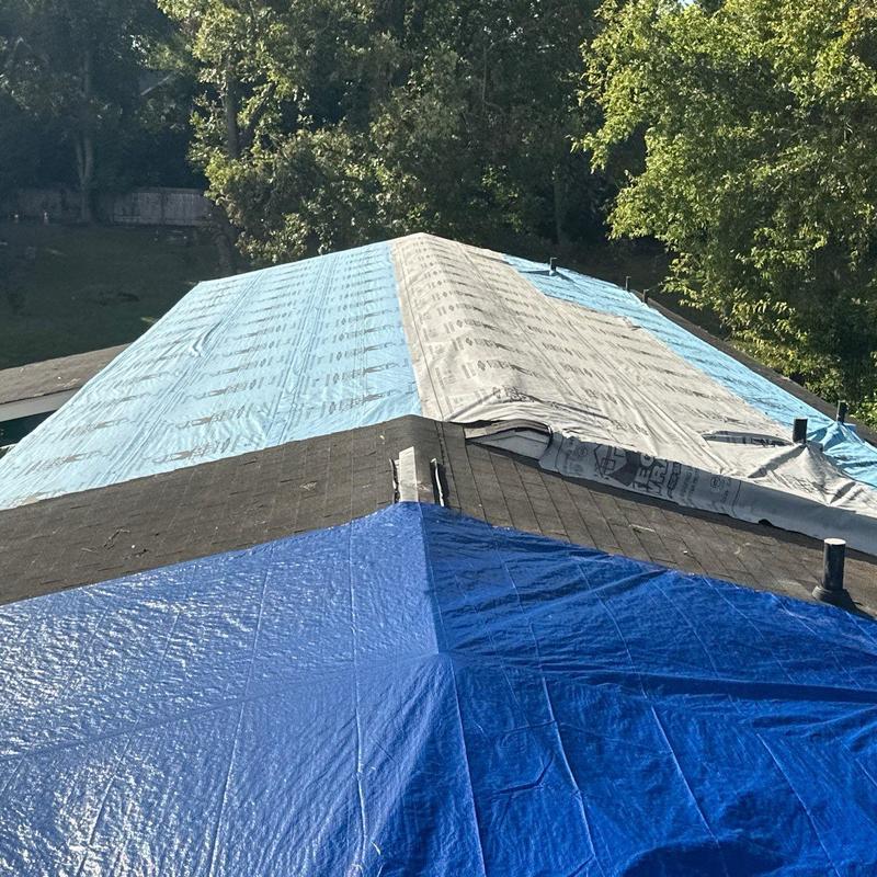 Asphalt shingle roof with protective tarps on ridge Asphalt shingle roof with protective tarps on ridge