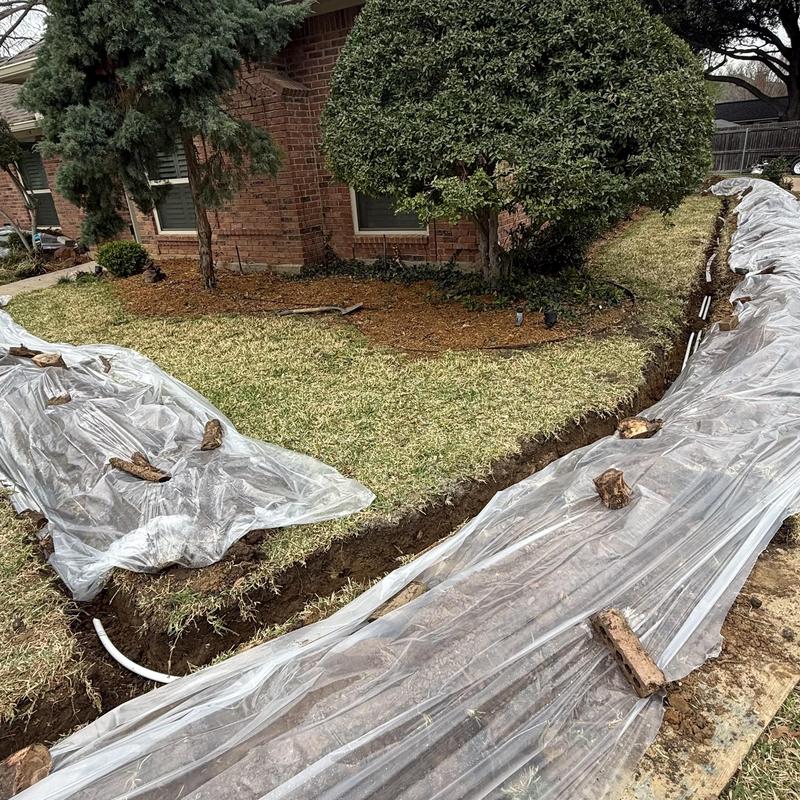 Water line trench covered with plastic in yard installation