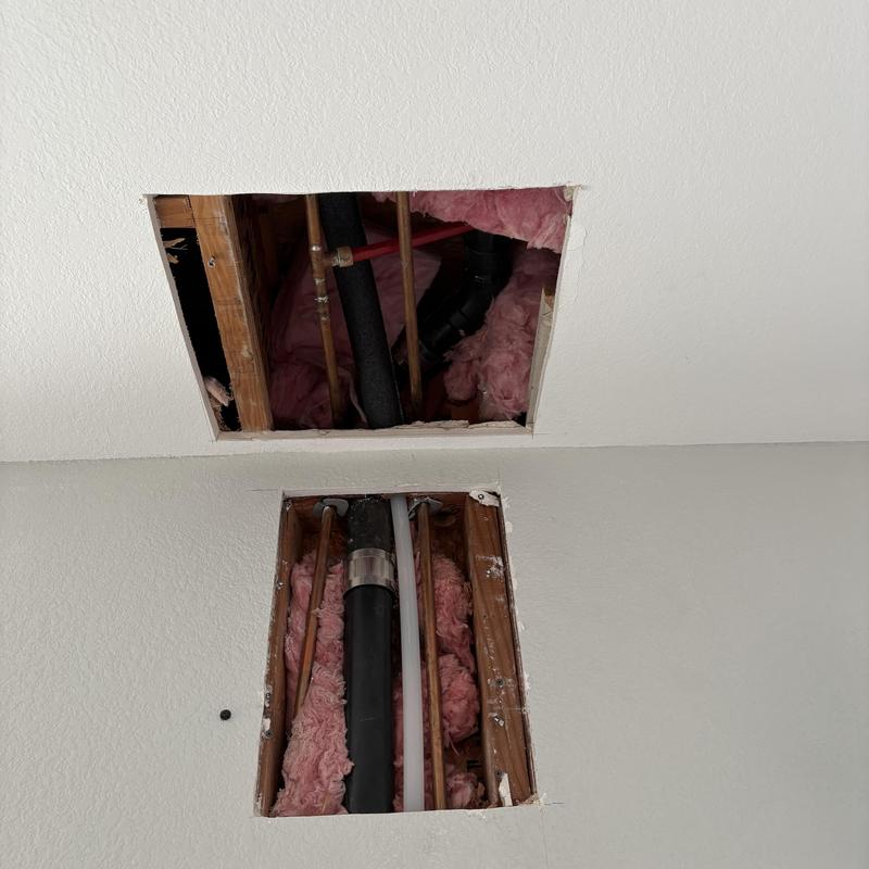 Plumbing pipes exposed behind drywall with insulation