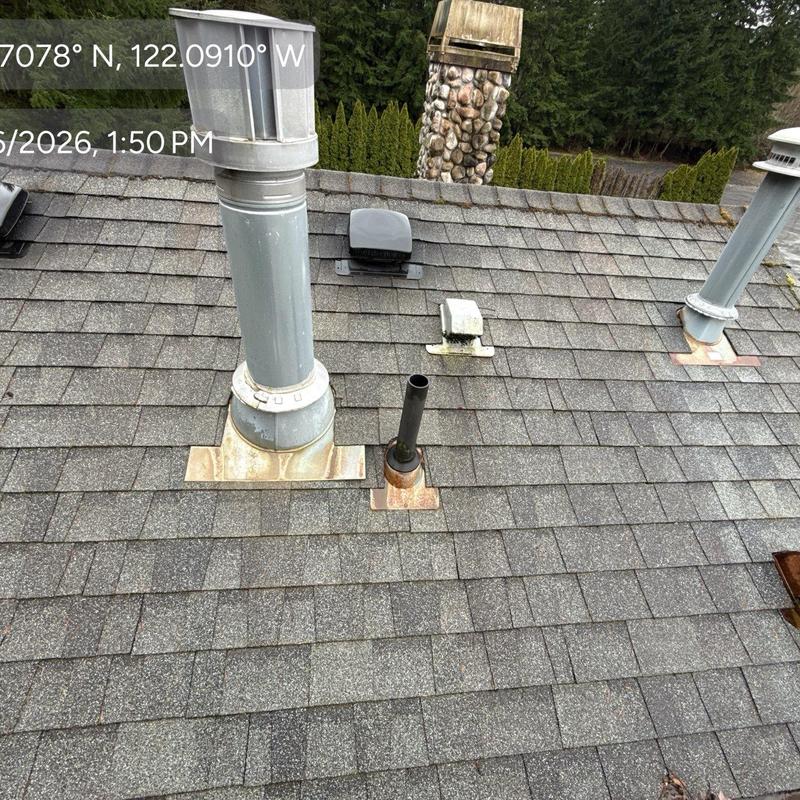 Roof vent flashing and shingle inspection on gray roof