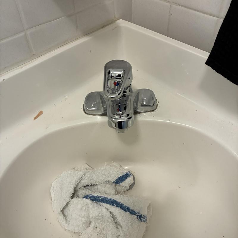 Bathroom sink faucet installation in white sink basin