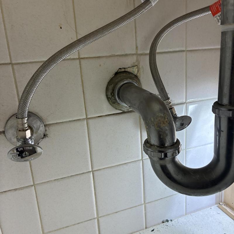 Bathroom sink drain pipe and supply lines under sink