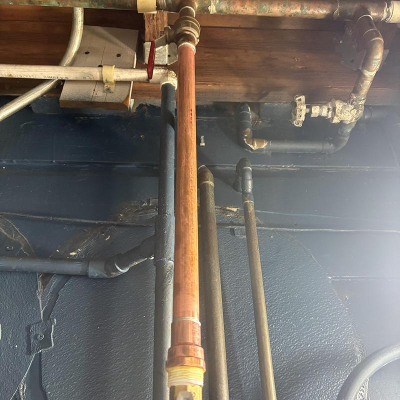 Copper water line with installed sub meter and surrounding pipes