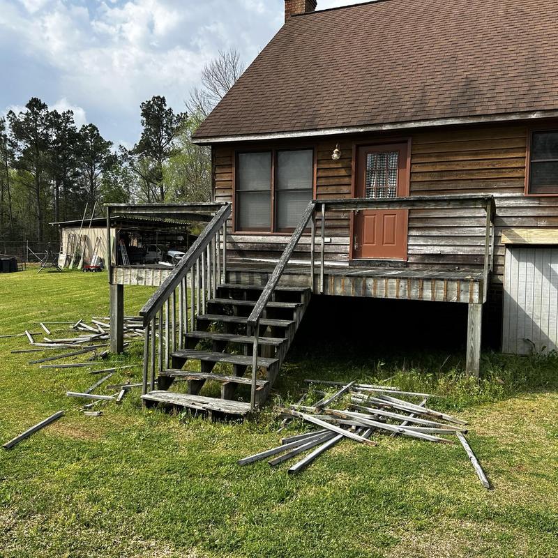 Wooden deck with stairs and scattered railing parts