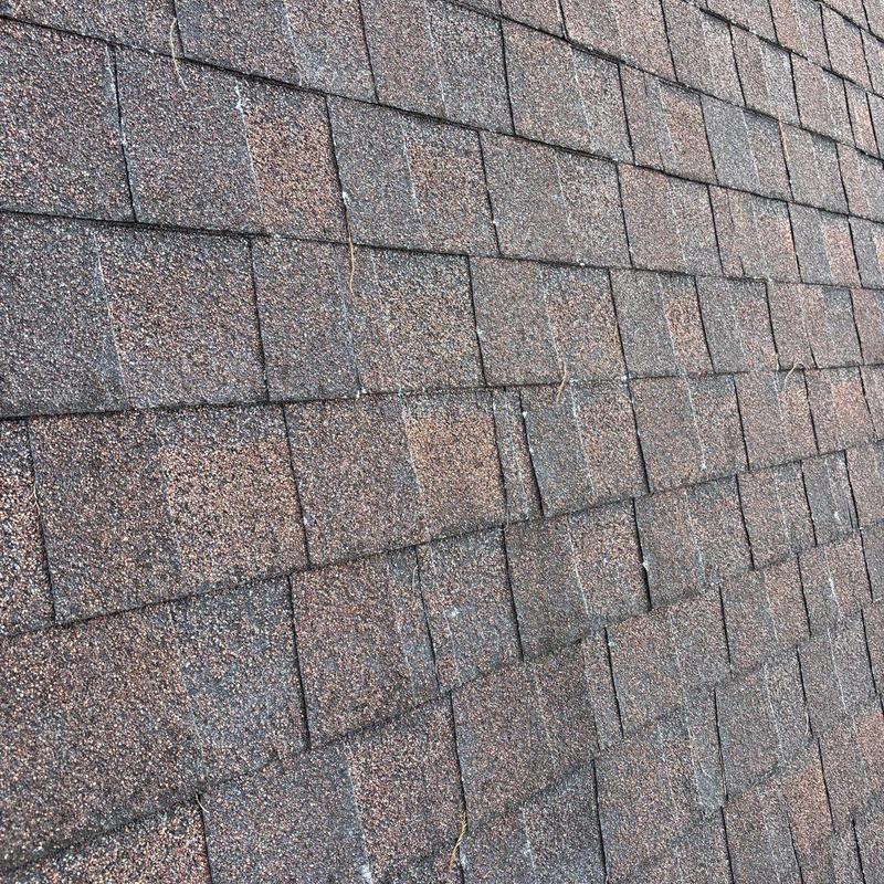 Asphalt shingles with visible hail damage on roof surface