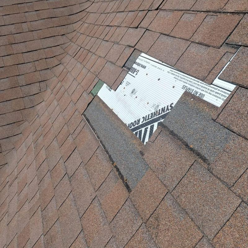 Storm damaged asphalt shingles with missing pieces on roof Storm damaged asphalt shingles with missing pieces on roof
