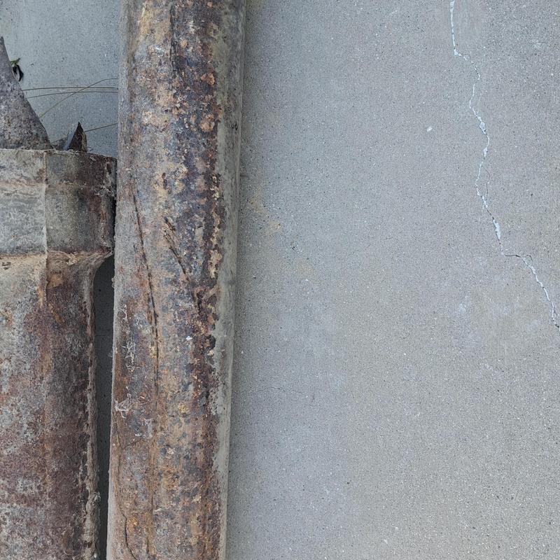 Rusty broken sewer pipe section removed on concrete floor