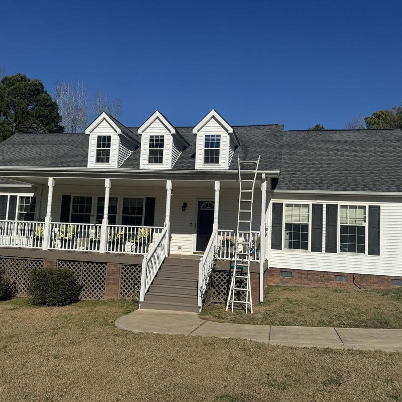 Asphalt shingle roof with ladder on white house