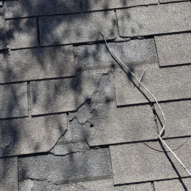 Damaged asphalt shingles with cracks and wear