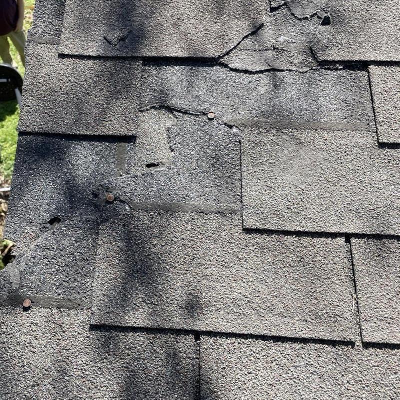 Damaged asphalt shingles with loose nails on roof