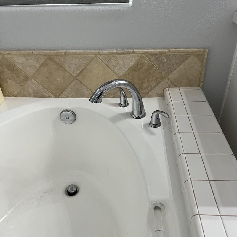 Roman tub faucet with chrome handles and white tiles