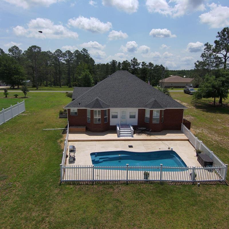 Asphalt shingle roof on brick home with backyard pool