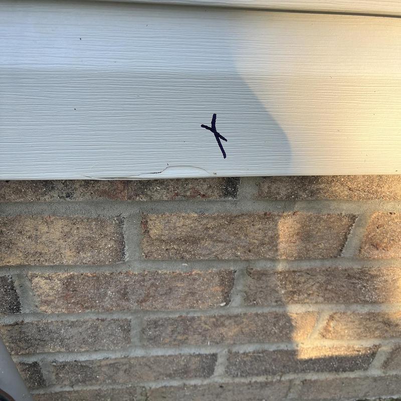 Vinyl siding damage marked on house exterior Vinyl siding damage marked on house exterior