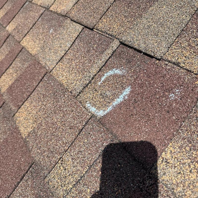 Asphalt shingle roof with hail damage marked for repair