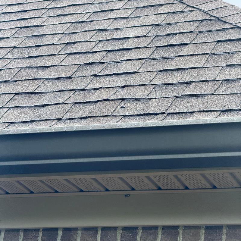 Asphalt roof shingles with hail damage near gutter